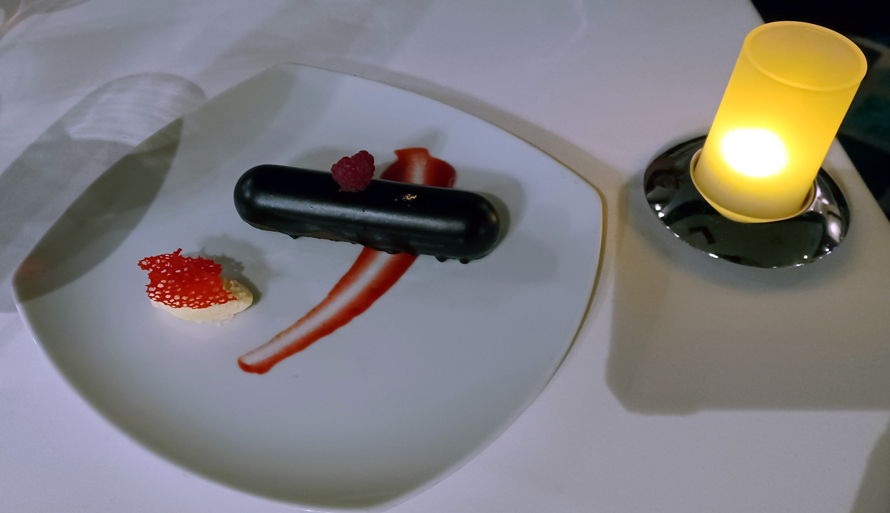 a plate of dessert with a candle and a black object on it