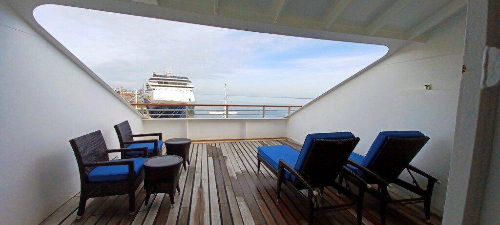 a deck with chairs and a cruise ship in the background