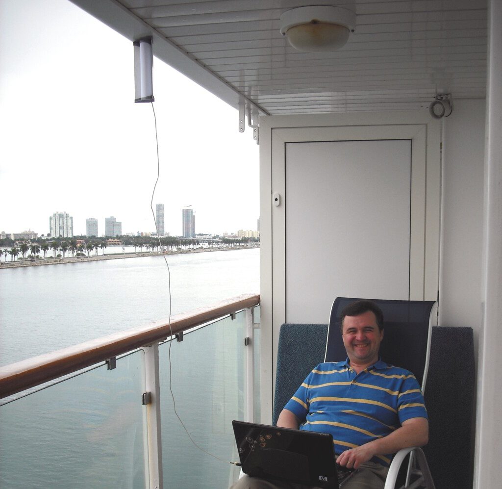 a man sitting in a chair with a laptop on a balcony