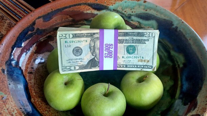 a bowl of green apples and a stack of money