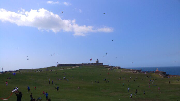 a group of people flying kites on a grassy hill