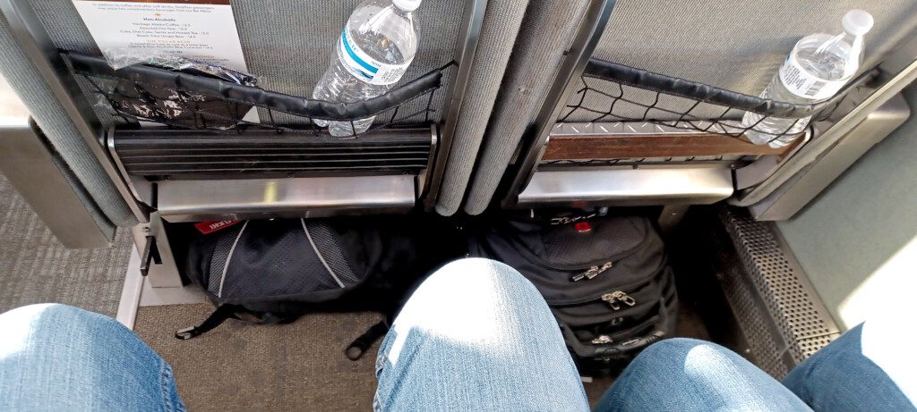 a person's legs and a bottle of water in a seat
