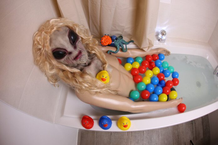 A very spooky alien is relaxing in the bathtub.
