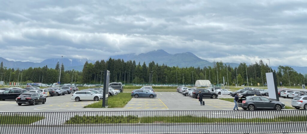 a parking lot with trees and mountains in the background