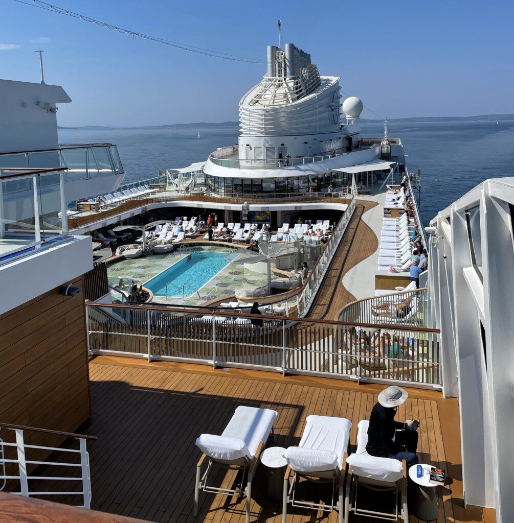 a deck of a cruise ship with a pool and people on it