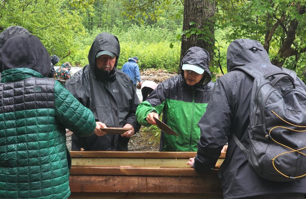 a group of people in raincoats standing near a wooden trough
