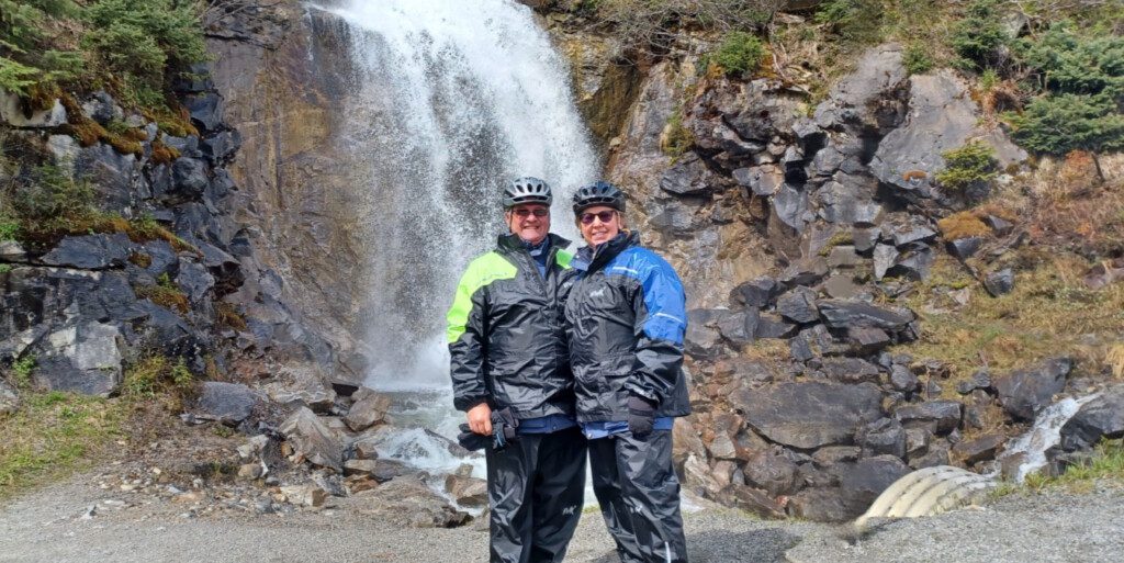 two people standing in front of a waterfall