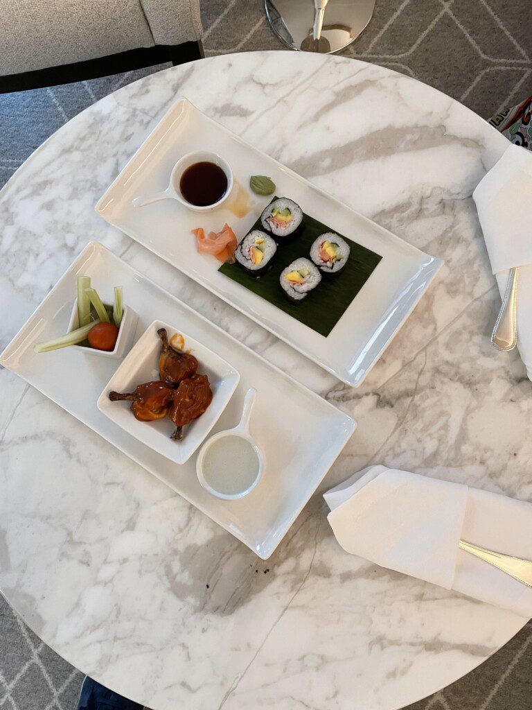 a plate of sushi and chicken wings on a marble table