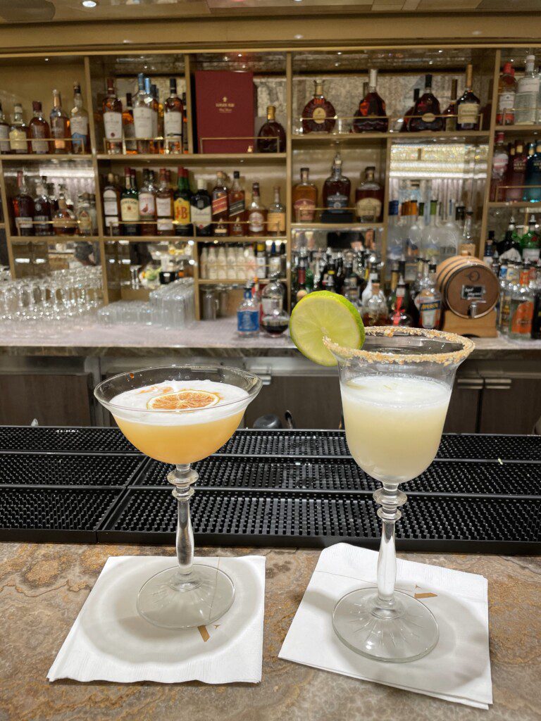 two glasses of drinks on a bar