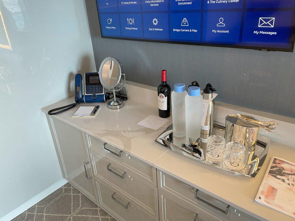 a counter with a mirror and a phone and a tray of wine
