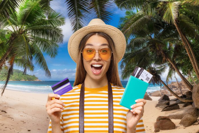 Excited traveler holding an airline boarding pass and a credit card