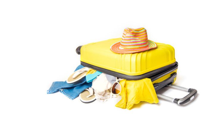 hat on a yellow suitcase with things of the traveler on a white background. concept rush travel fees.