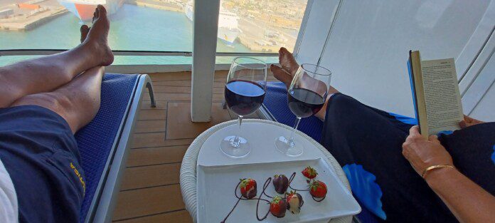 a person's feet on a deck with wine glasses and strawberries