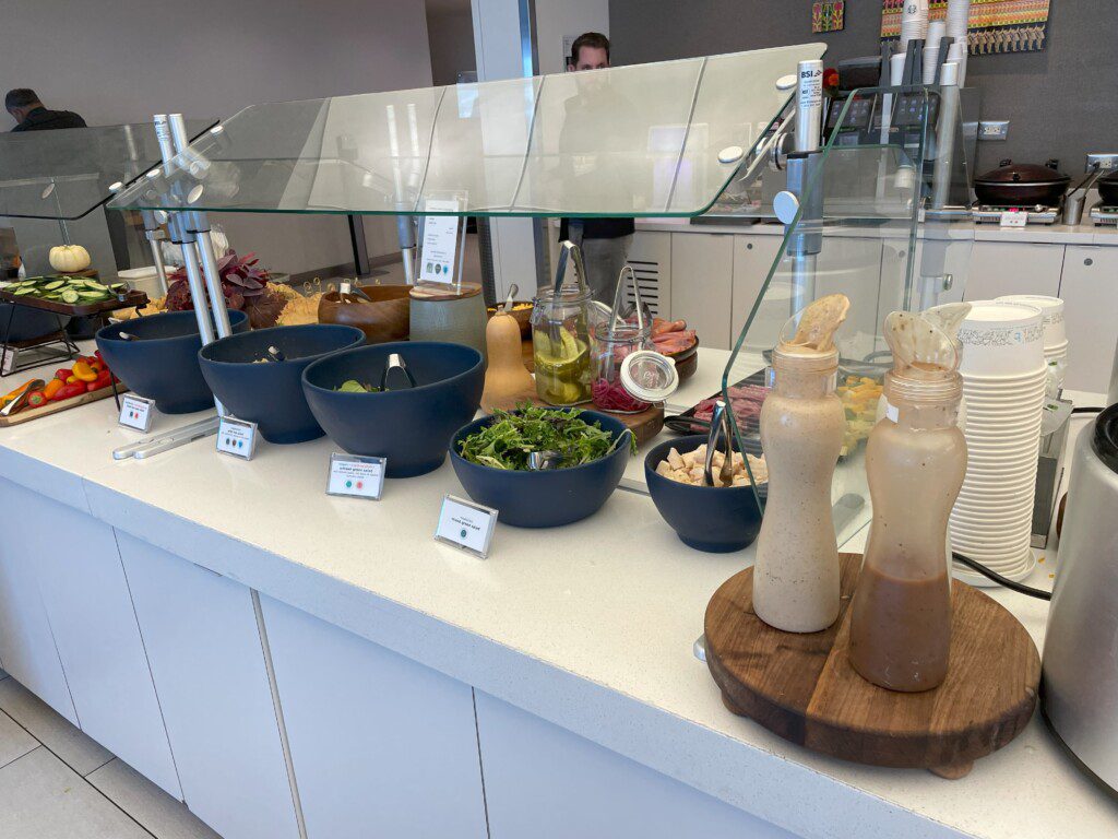 a counter with bowls of salads and bottles of sauces