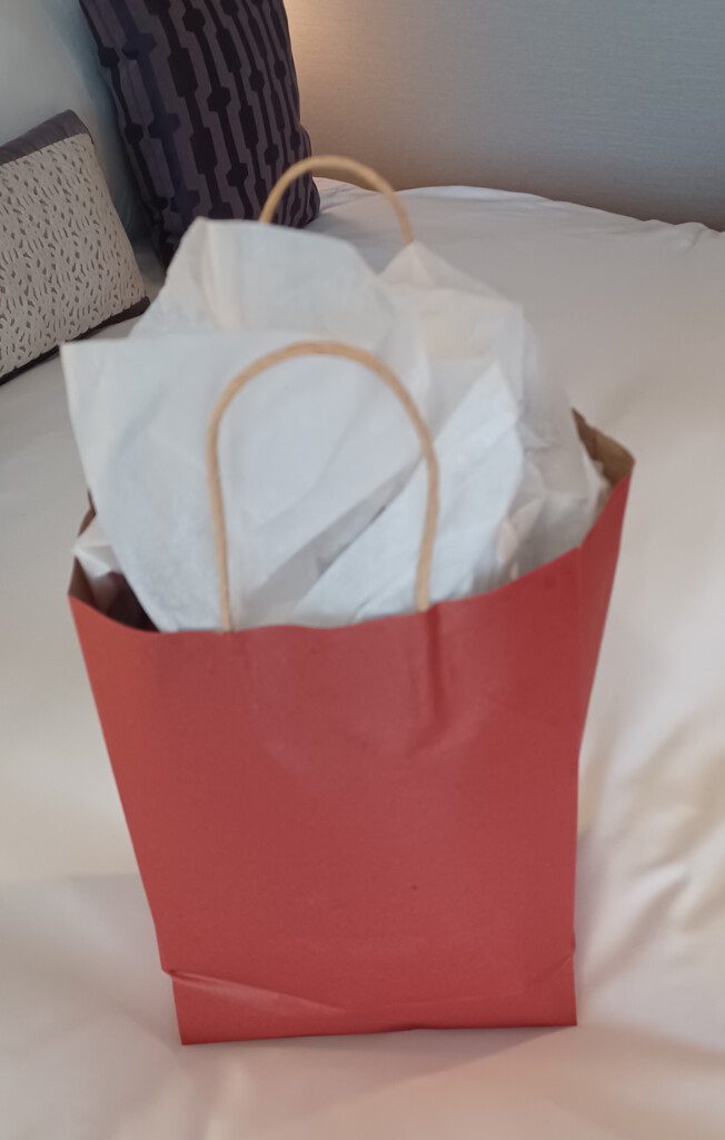 a red bag with white paper and a handle