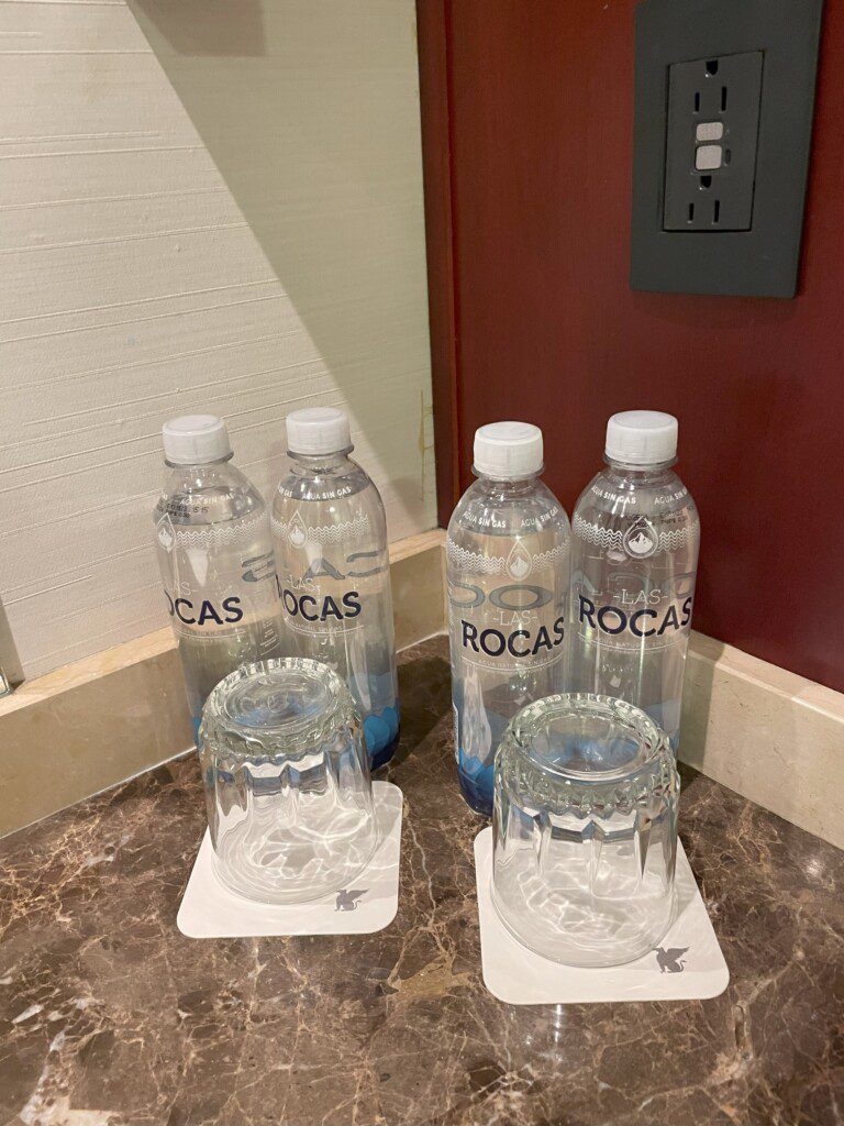 a group of water bottles and glasses on a marble surface