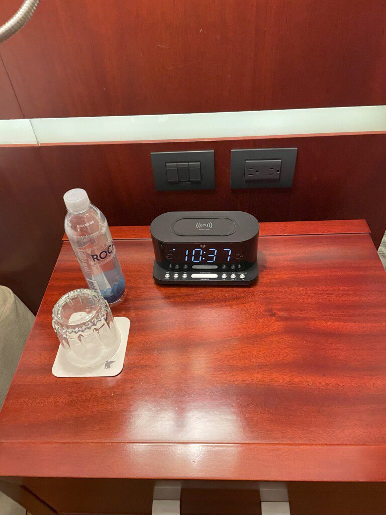 a alarm clock and a bottle on a table