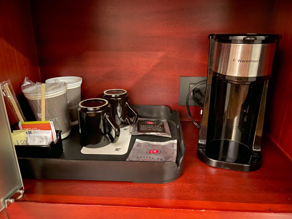 a coffee maker and mugs on a tray