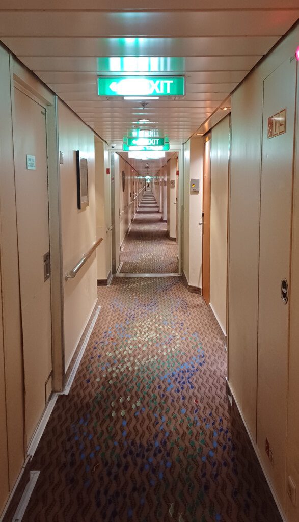 a long hallway with doors and a green sign