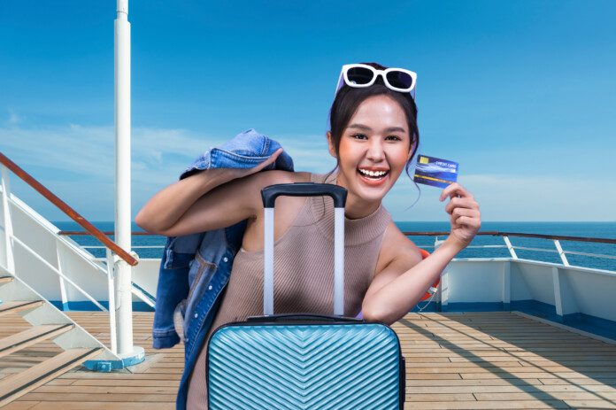 a woman holding a credit card and holding a suitcase on a cruise ship deck