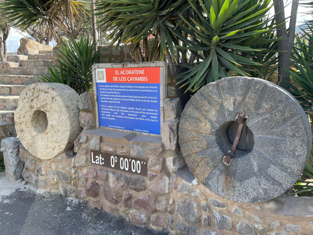 a stone wall with a sign and a stone wheel