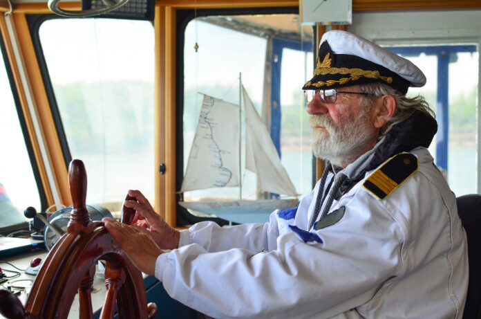 Ship navigation, experienced captain, old sea dog with grey hair and beard on his working place, ship navigation cabin