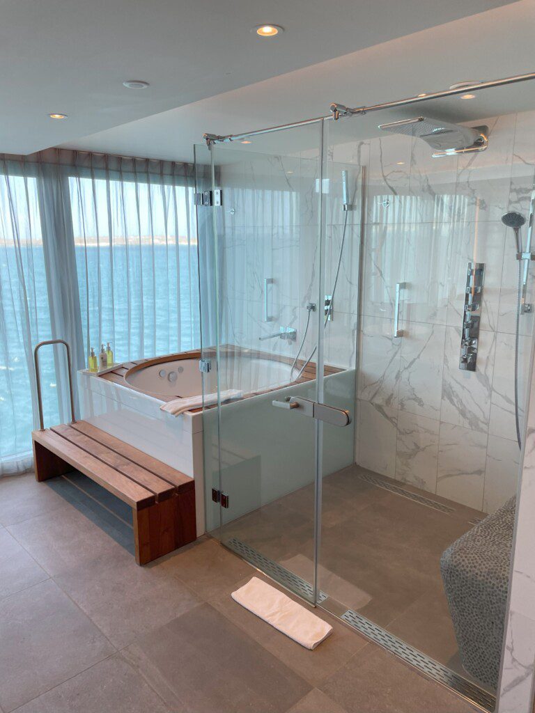 a bathroom with a glass shower and a bench