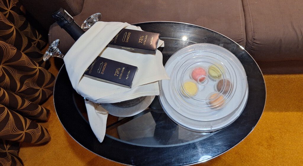 a plate of macaroons and a bag of luggage on a glass table