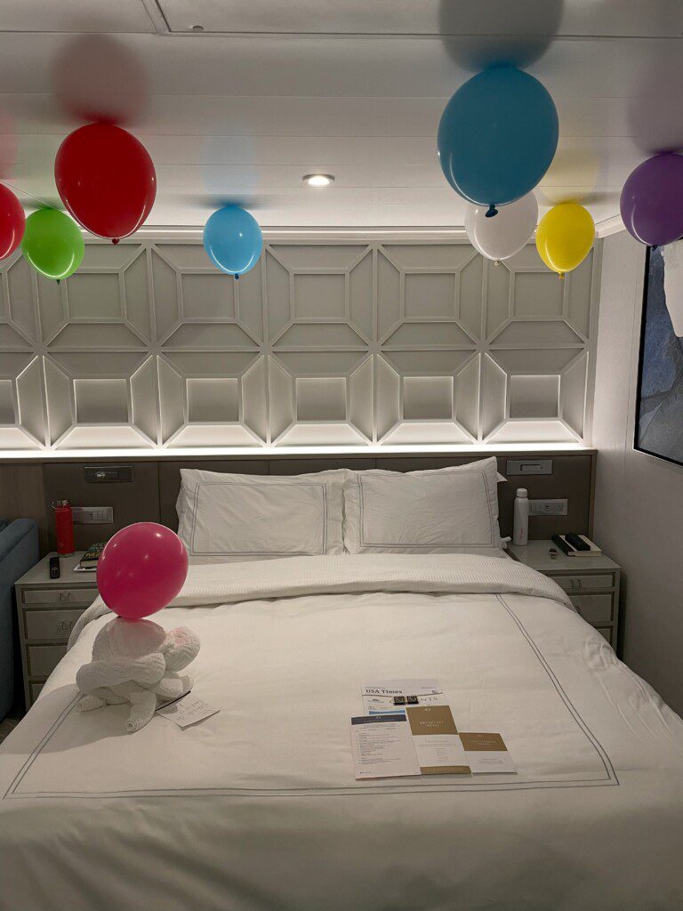 balloons on a bed with a stuffed animal on it