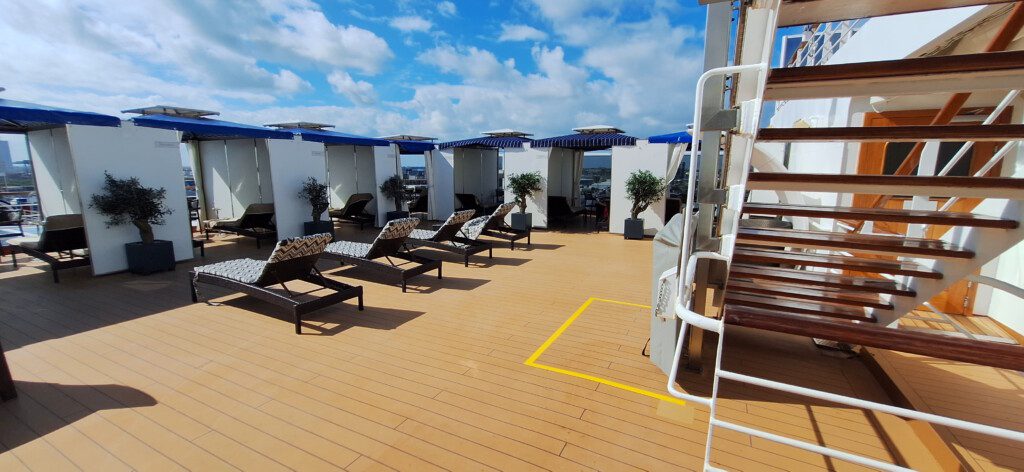 a deck with lounge chairs and a deck chair on a cruise ship