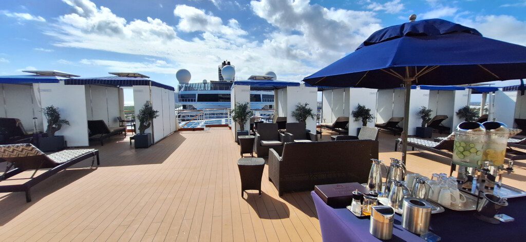 a deck with chairs and tables on a cruise ship