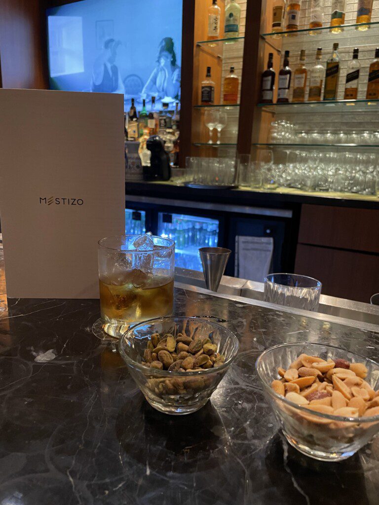 a bar with a glass of alcohol and bowls of nuts