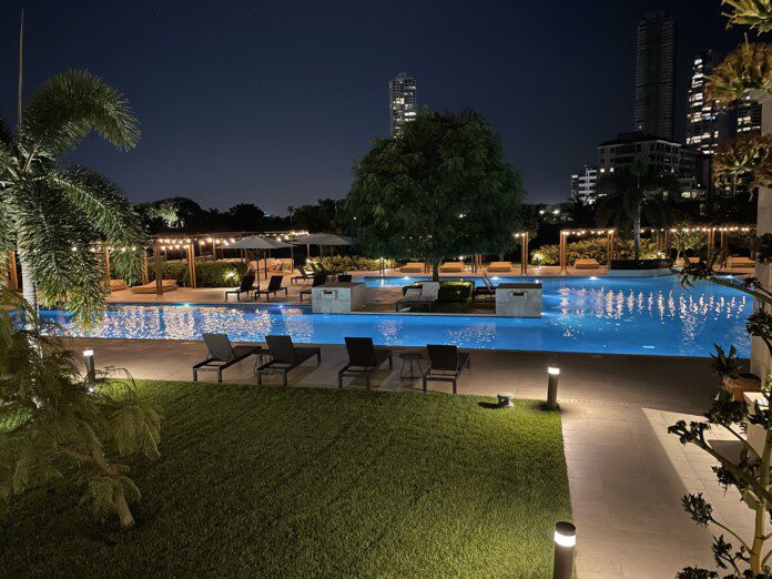 a pool with chairs and trees at night