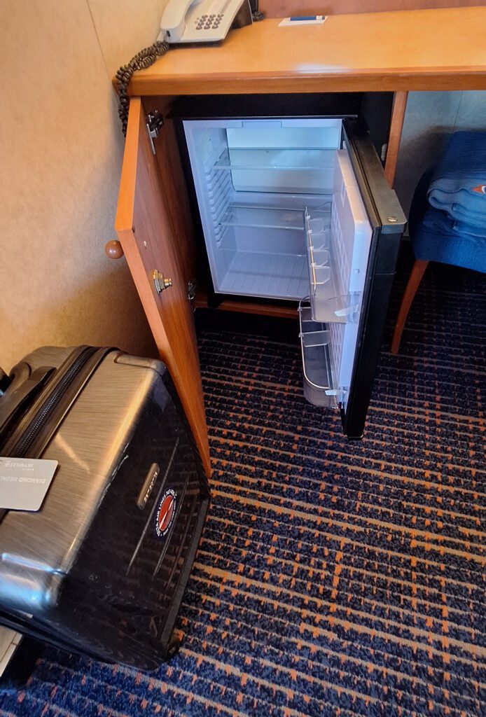 a small refrigerator with a suitcase in the corner of a room