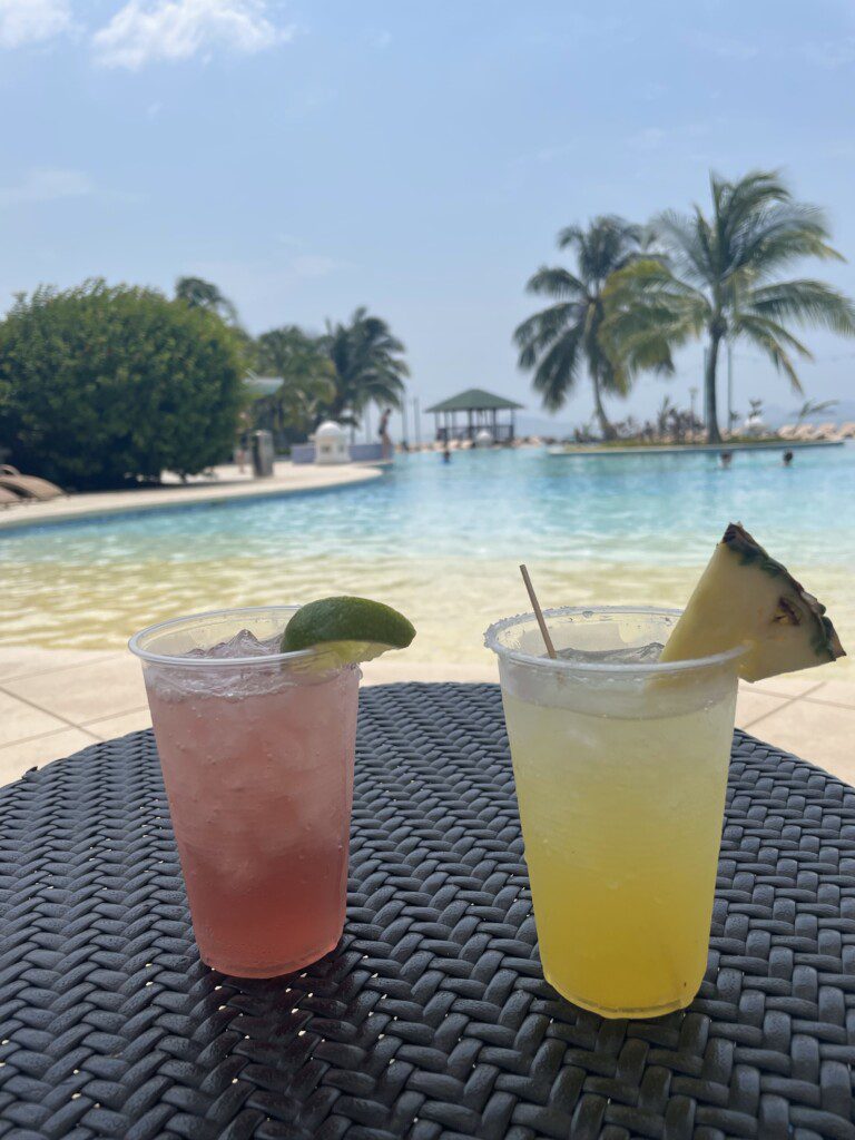 two drinks on a table by a pool