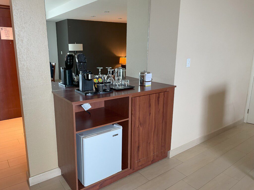 a counter with a small refrigerator and coffee maker